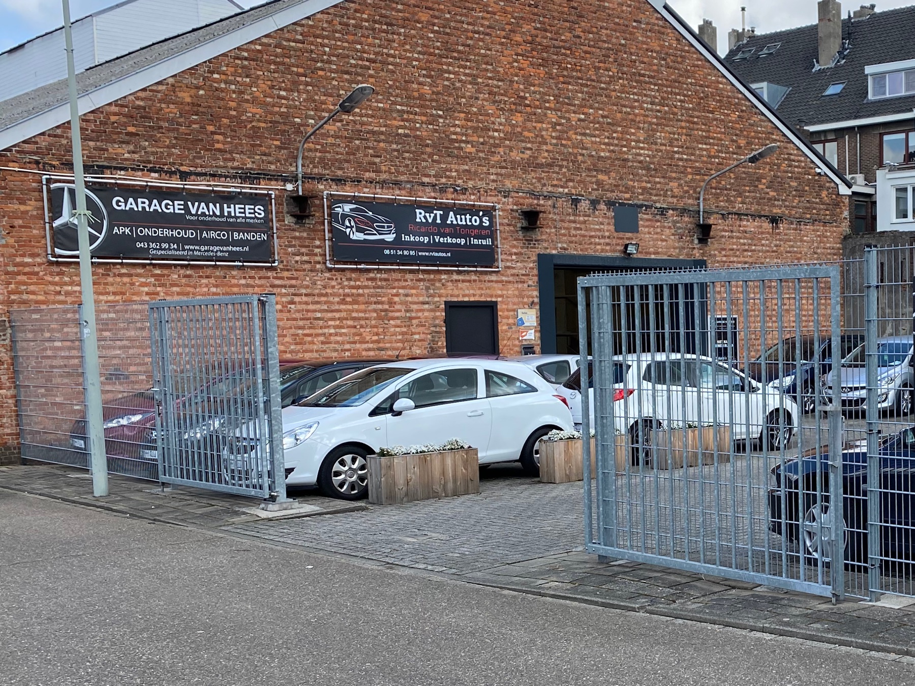 Het naambord Garage van Hees met de Mercedes-ster op de bakstenen gevel, met het hek ervoor