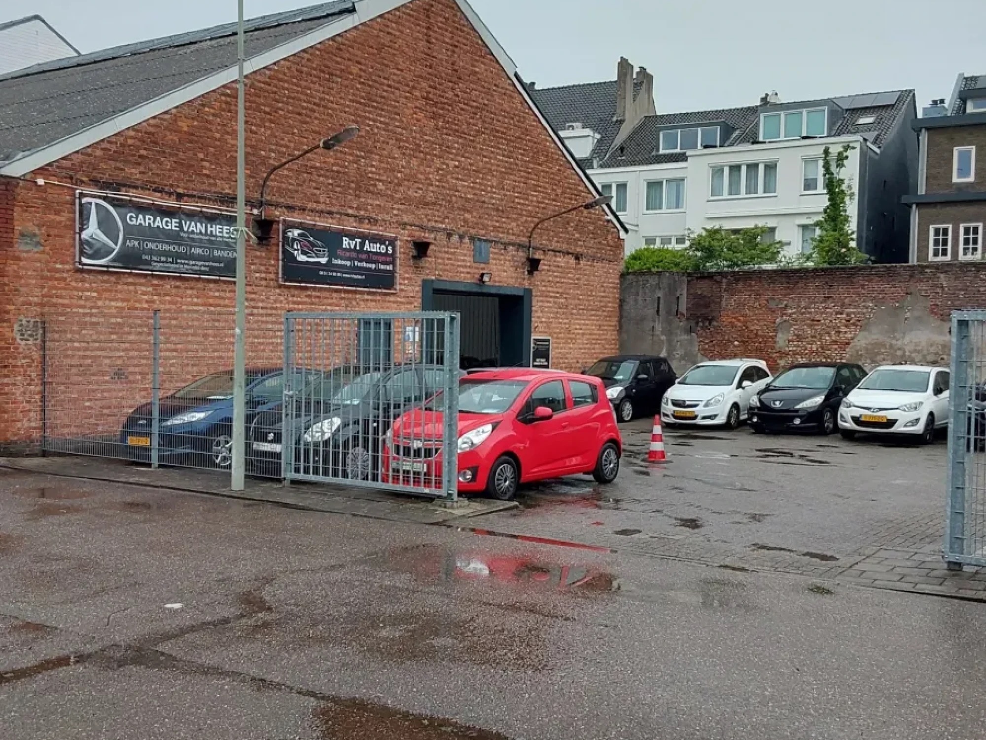 Het terrein van Garage van Hees met de gevel en geparkeerde auto's