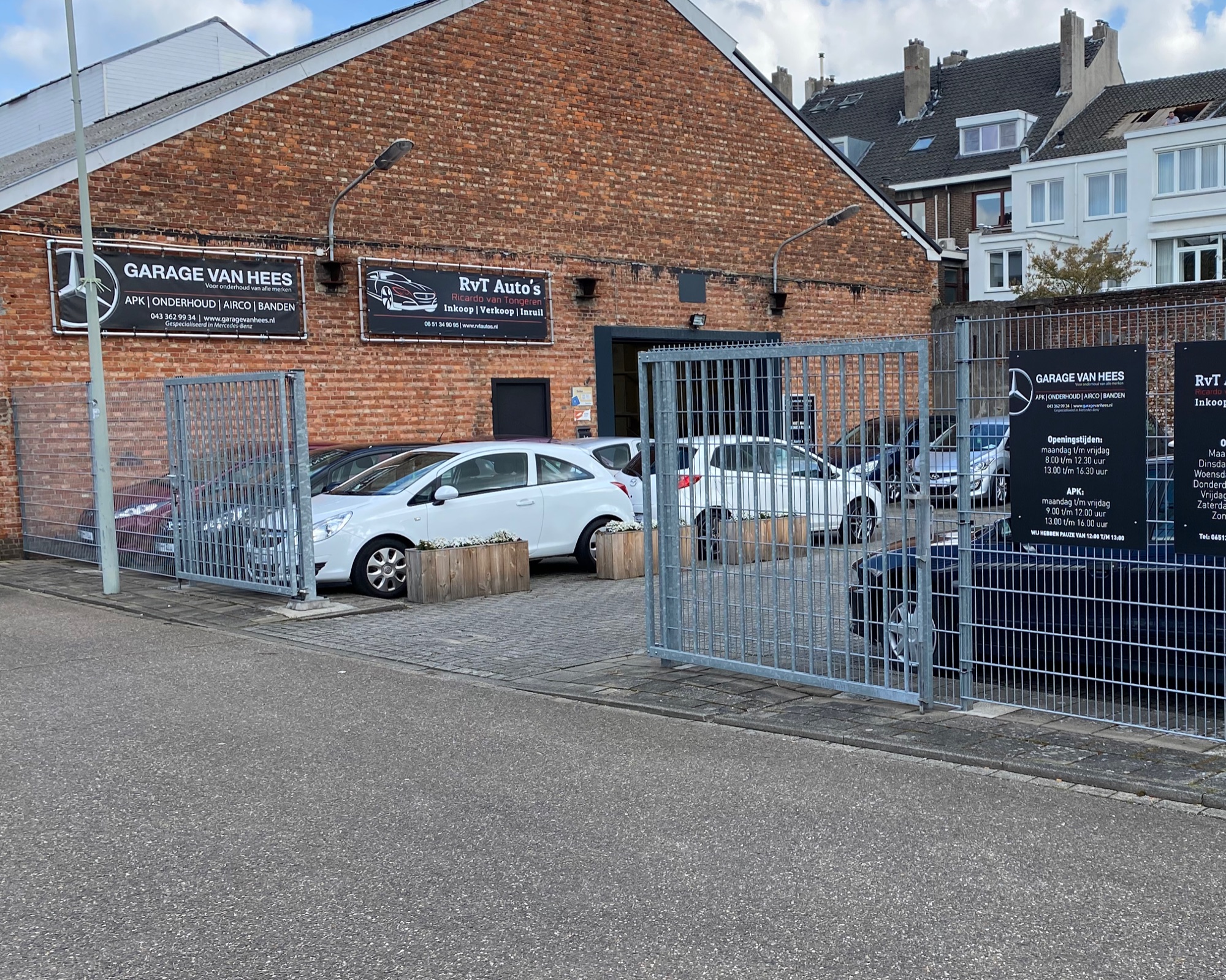 De garage aan de Scharnerweg in Maastricht: bakstenen gevel met het zwarte naambord Garage van Hees en het hek met de openingstijden