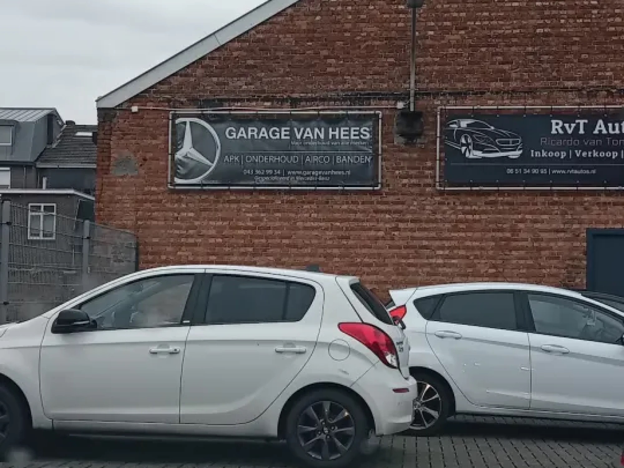 De gevel van Garage van Hees met het naambord en een rij auto's op het terrein