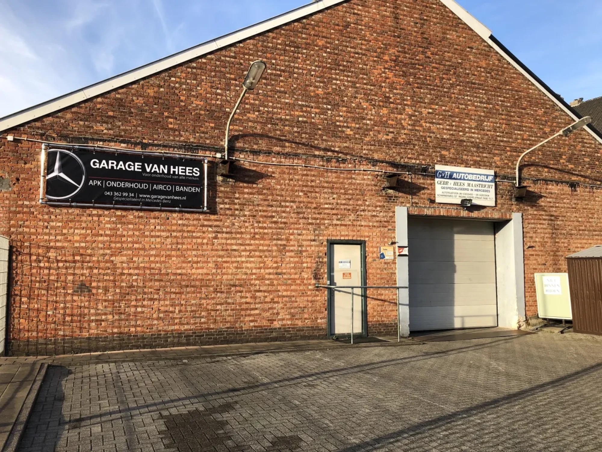 Het naambord Garage van Hees met de Mercedes-ster op de bakstenen gevel, in de zon